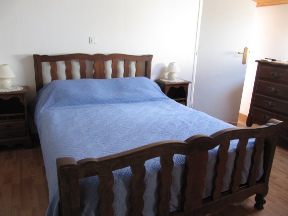 lit avec dessus de lit bleu et velux au deesus d'une vieille commode