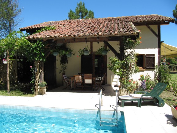 piscine bleue avec margelle blanche et la terrasse ombragée de l'annexe
